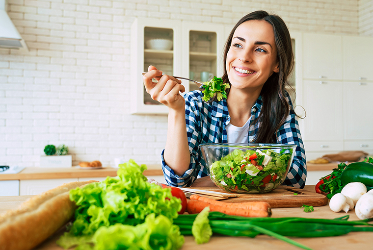 B12 Ankermann: Eine junge Frau befindet sich in einer Küche und isst frischen Salat.