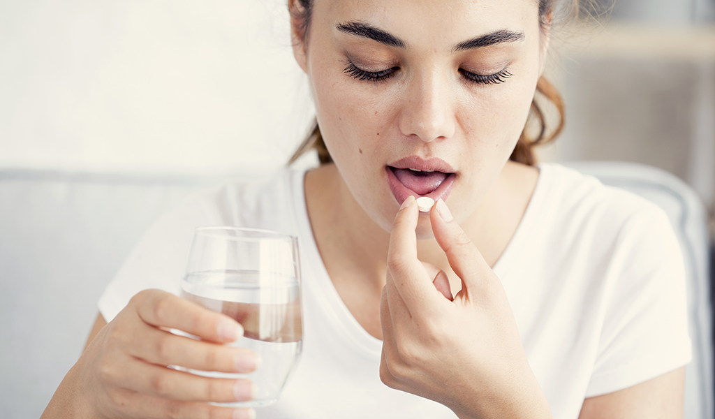 Frau nimmt ein Vitamin B12-Präparat ein – eine Vitamin B12-Überdosierung ist dabei äußerst selten.